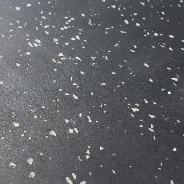 Close-up of the Bells of Steel Rubber Flooring Gym Mat 24" x 24" (Set of 2) shows a dark, textured surface with white specks and small shards, ideal for heavy-duty home gym flooring setups.