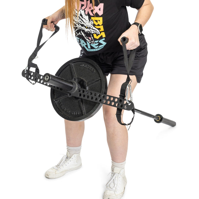 A person in a black graphic tee, black shorts, and white sneakers demonstrates a landmine row using the Bells of Steel 30 D-Handle Bar Cable Attachment with Carabiners, weight plates, and resistance straps against a white background.