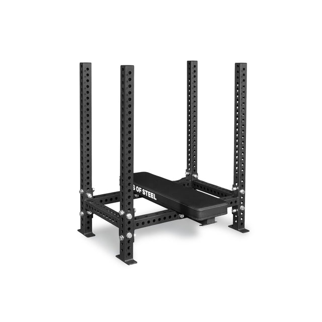 The Bells of Steel Manticore Four Post Converter Bench is a black steel squat rack with four uprights featuring multiple adjustment holes and a padded bench, ideal for weightlifting and strength training.