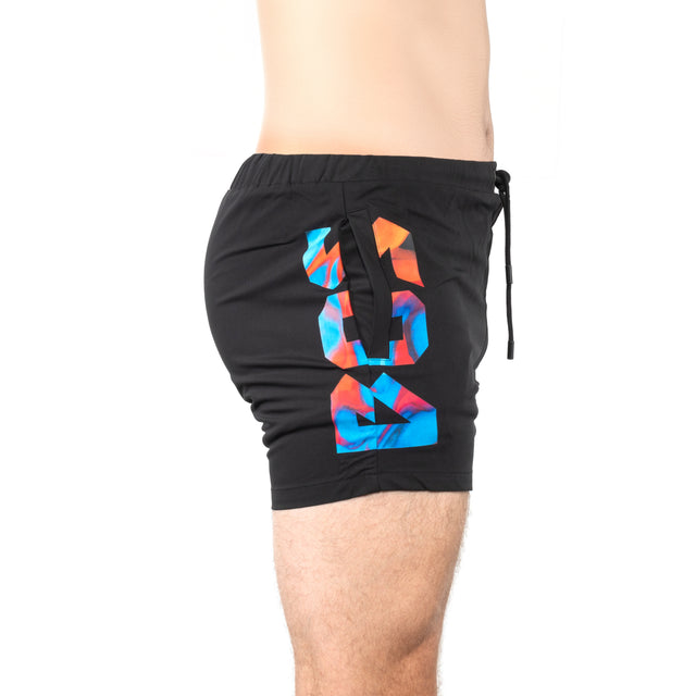 A model wears Bells of Steel Gym Shorts featuring a colorful geometric "99" on the left side, made from stretchy fabric, shown waist to mid-thigh in side profile against a white background.
