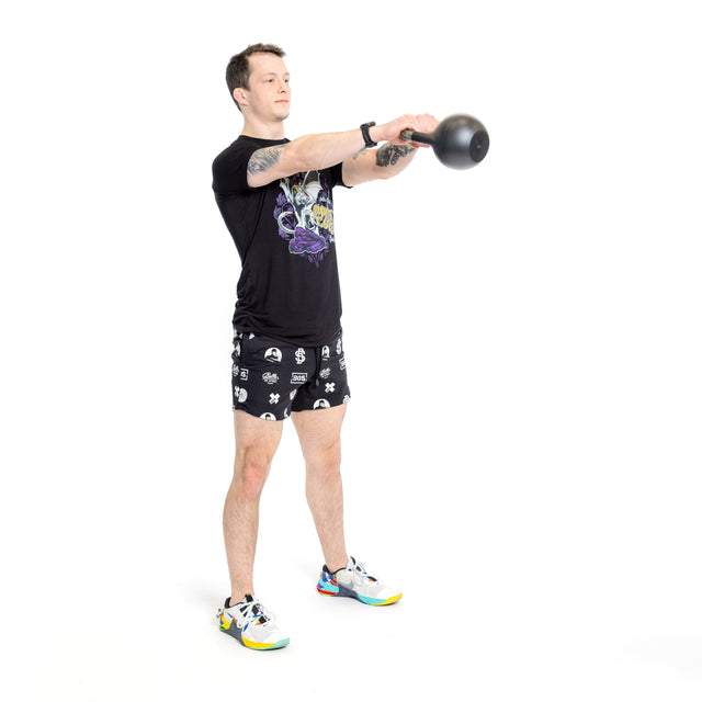 A person wearing Bells of Steel Gym Shorts made from high-performance materials does a kettlebell swing, holding the weight with both hands at shoulder height against a plain white background.