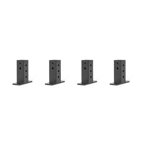 Four black, rectangular metal brackets with multiple holes, likely used as wall connectors for Hydra & Manticore racks from Bells of Steel, are arranged in a row against a plain white background.