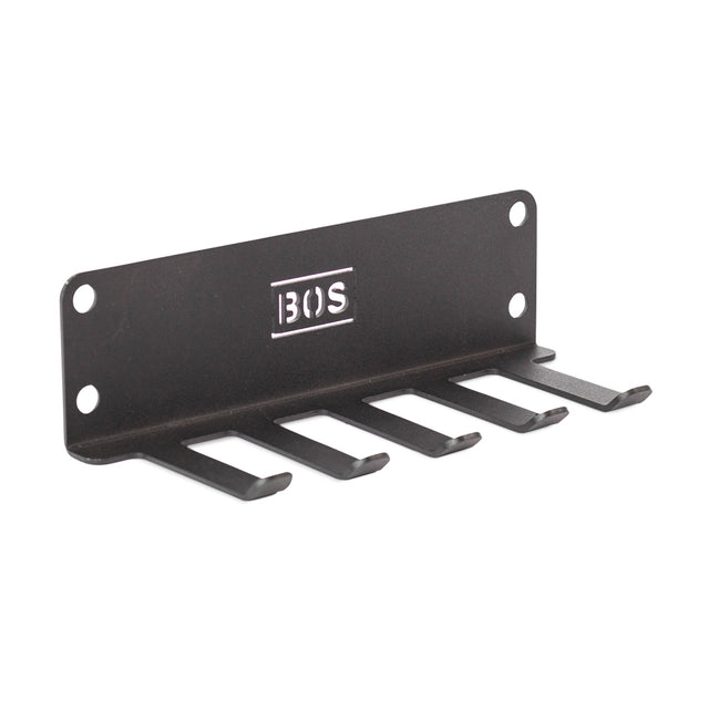 The Bells of Steel Accessory Holder is a black metal wall or Hydra-mounted rack organizer with five flat hooks, four mounting holes, and "BOS" engraved in the center—perfect for gym storage.