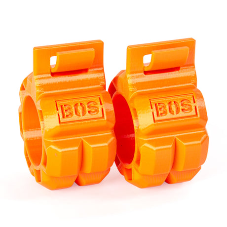 Two bright orange Barbell Zip Clips by Bells of Steel, featuring a chunky, barbell-inspired design. "BOS" is engraved on each clip. These plastic clips have a pressure-cuff-like design with rectangular tabs for securing against a plain white background.