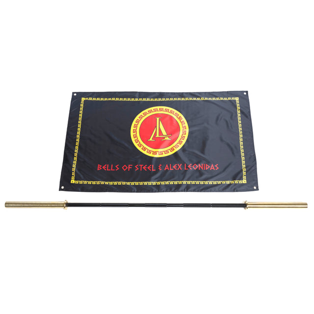 A black flag with a gold and red Spartan-style logo and "BELLS OF STEEL & ALEX LEONIDAS" text is displayed above the Bells of Steel Alex Leonidas Onyx Bar, a gold and black Cerakote-finished power bar, on a white background.