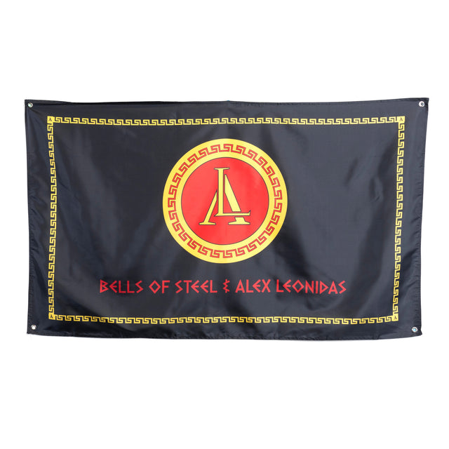This black flag showcases a Greek key border, a red and yellow emblem with an "L," and "BELLS OF STEEL & ALEX LEONIDAS" in red—ideal for fans of the Bells of Steel Alex Leonidas Onyx Bar.