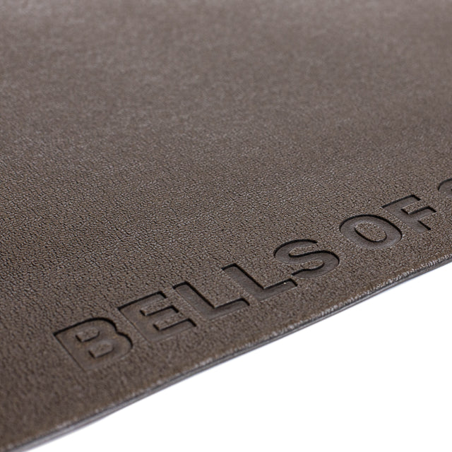 A close-up of a textured brown Bells of Steel Cardio Machine Floor Mat, with the embossed brand name partially visible near the edge.