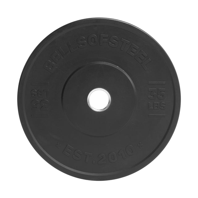 The Bells of Steel All-Black Bumper Plate features "35 LBS" on the right, "EST. 2010" at the bottom, and precise weight accuracy, plus a central hole for easy loading onto barbells.