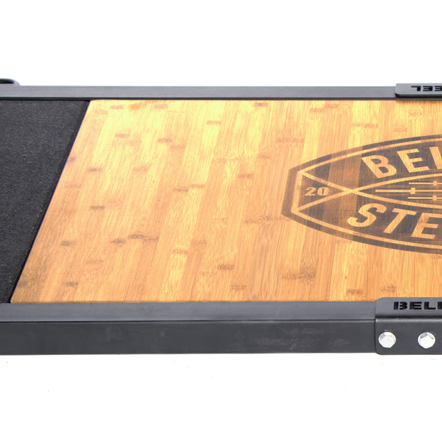 A close-up of the Deadlift Platform Bamboo Insert (Left) by Bells of Steel, showing its rectangular bamboo surface with a partial black “BEL” and “STE” logo, framed by black metal edges with visible screws.
