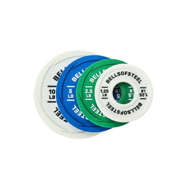 Four round Urethane-Coated Change Plates in white, blue, green, and white are stacked diagonally. Each plate features the "Bells of Steel" brand name and displays its weight in pounds.