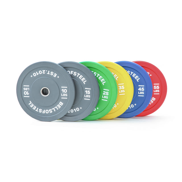 Six Coloured Bumper Plate Sets by Bells of Steel—gray (10 lbs), green (25 lbs), yellow (35 lbs), blue (45 lbs), and red (55 lbs)—feature branded logos, precise weight markings, and stainless steel inserts.