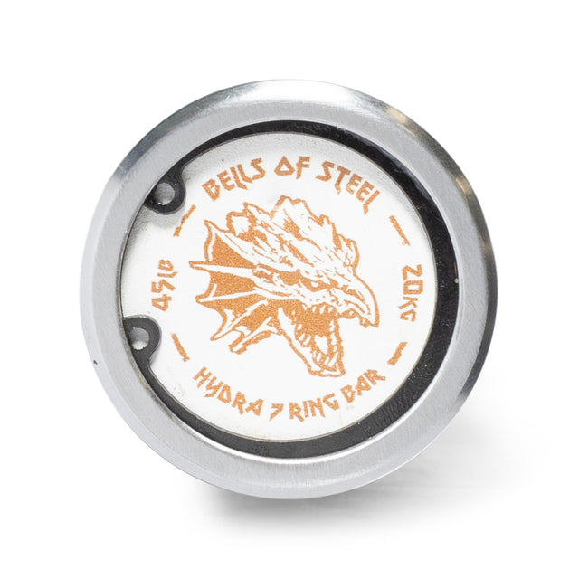 A close-up of the Hydra Seven Ring Bar end cap by Bells of Steel, featuring a stylized dragon head and "45LB" and "20KG" in gold on a white background.