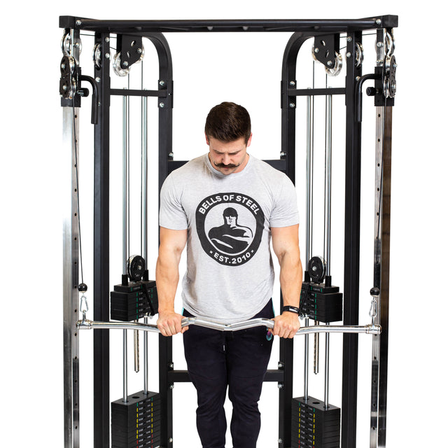 A man in a gray Bells of Steel t-shirt uses the Bells of Steel Double Hook EZ Curl Bar Cable Attachment, gripping it with both hands and pulling it down in front of him against a plain white background.