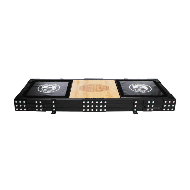 The Bells of Steel Weightlifting Platform is a rectangular black folding table with domino designs on the legs and corners, resembling a lifting platform. It has a wooden center tabletop with black sides displaying circular game-themed logos.