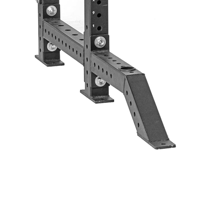 A close-up of Bells of Steel Front Foot Stabilizers shows the base and angled support with multiple attachment holes and heavy-duty bolts securing the black metal frame of a power rack.
