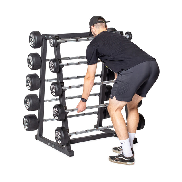 A person in black attire is bending over to lift a barbell from the Bells of Steel Fixed Barbell Rack, which holds multiple weights, against a plain white background.