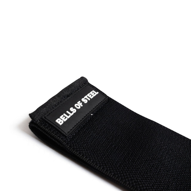 The Bells of Steel Glute Loop is a black fabric resistance band with a non-slip design and a sewn-on "BELLS OF STEEL" label, shown against a white background.