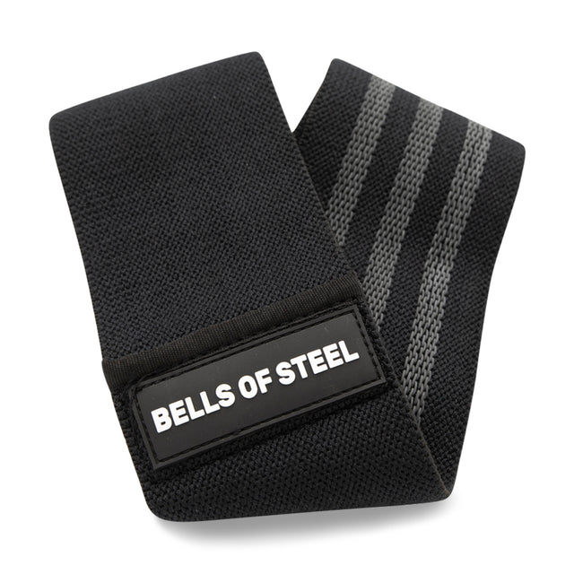 The Glute Loop by Bells of Steel is a black, non-slip resistance band with two gray stripes and a white "BELLS OF STEEL" label, neatly folded and ready to boost your next booty workout.