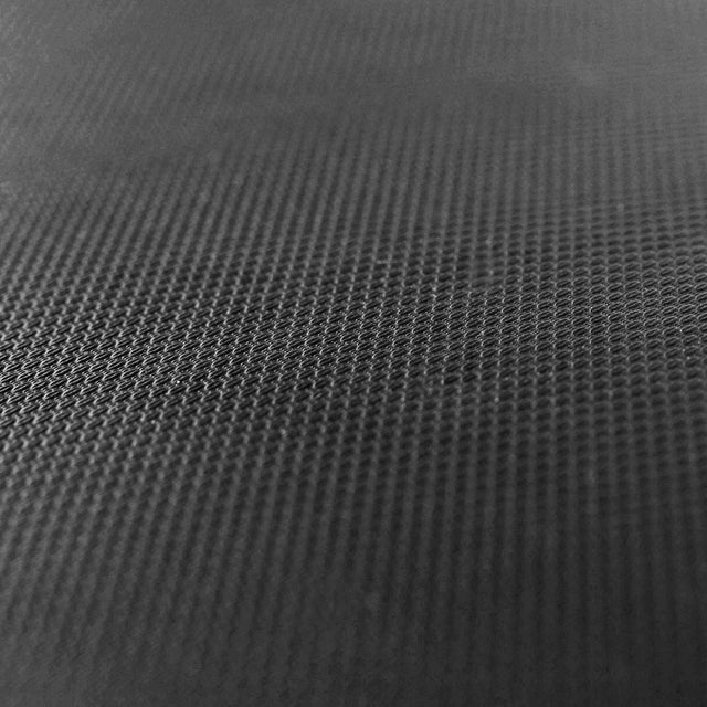 Close-up of the textured black surface of the Bells of Steel Hero Heavy-Duty Weight Bench, showcasing a repeating small mesh pattern that gradually fades out of focus toward the top.