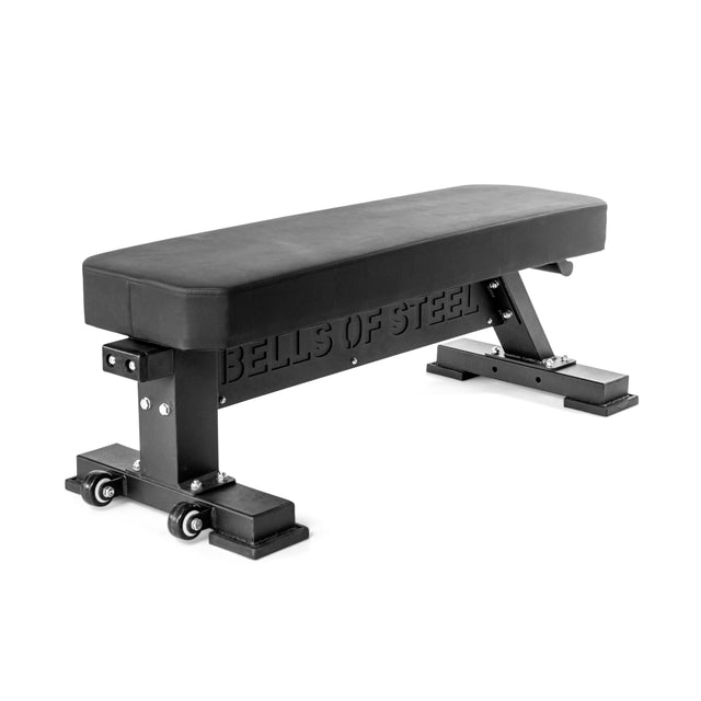 The Bells of Steel Hero Heavy-Duty Weight Bench features a padded top, sturdy steel legs, built-in wheels for easy movement, and the brand’s logo cut into the frame—perfect for gym or home workouts.