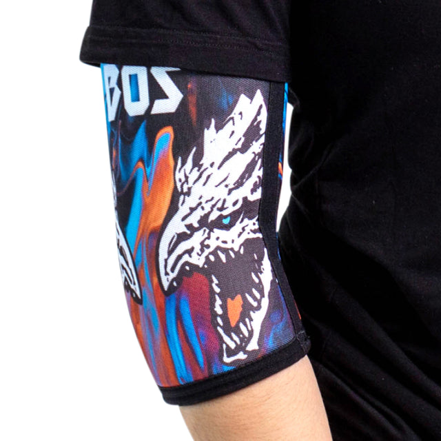 A person is wearing a black T-shirt and Bells of Steel Elbow Sleeves with a vibrant design featuring a fierce white dragon or wolf head, accented in blue, orange, and black.