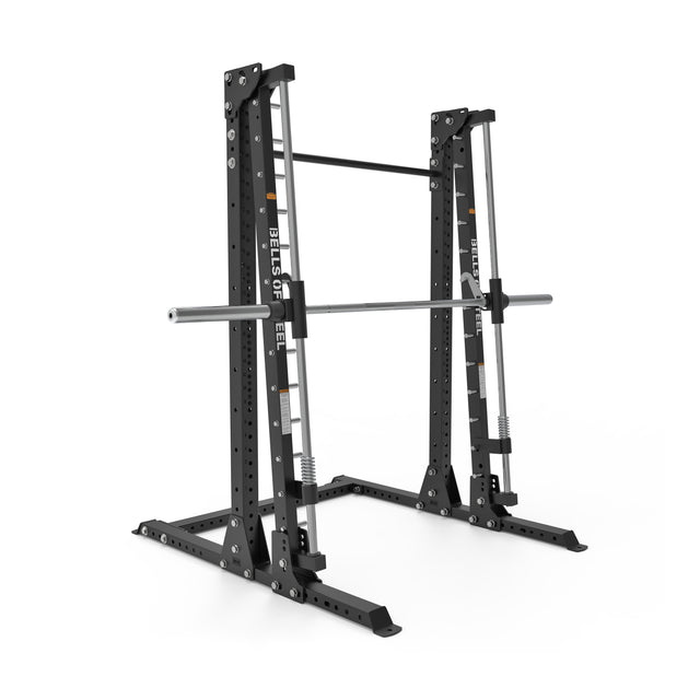 A black Bells of Steel Smith Machine - Hydra (3" x 3", ⅝" Holes) with adjustable safety arms and a horizontal pull-up bar supports a silver barbell. This heavy-duty, free-standing rack is pictured on a white background.
