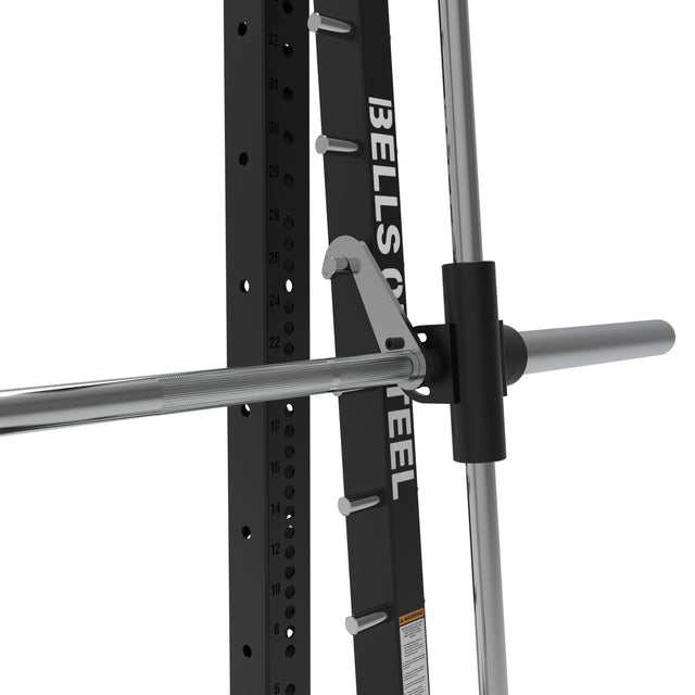 Close-up of a Smith Machine - Hydra (3" x 3", ⅝" Holes) barbell on its rack, safety hooks attached, with the Bells of Steel logo visible on the vertical support.