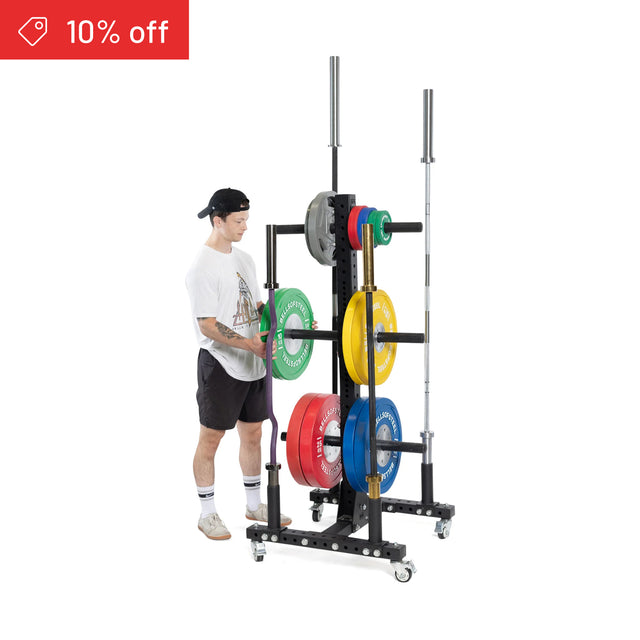 A man in athletic wear arranges colored weight plates on a Bells of Steel Hydra Bumper Plate Tree Builder, a black wheeled gym storage rack with two barbells. A red banner at the top left reads “10% off.”.