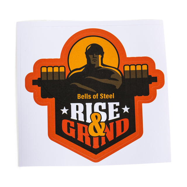 A durable Bells of Steel sticker features a muscular figure with a barbell, “Bells of Steel” above, and “Rise & Grind” below in bold yellow and orange on high-quality vinyl. The black, yellow, and orange design stands out.