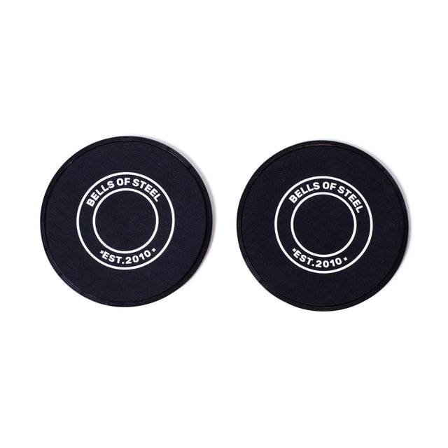 Two black Bells of Steel Core Sliders, featuring "BELLS OF STEEL EST. 2010" in white text at the center, are shown side by side on a white background—ideal for enhancing any total body workout routine.