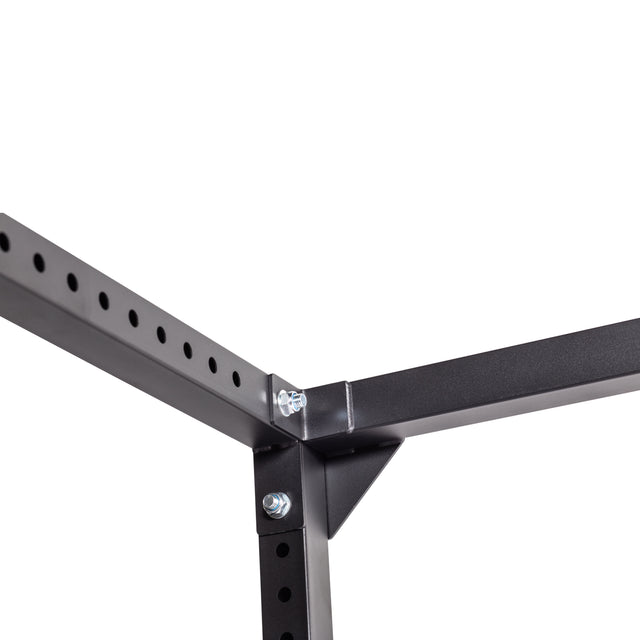 Close-up of the Bells of Steel Light Commercial Power Rack (2.3" x 2.3", ⅝" holes) corner, showing three connected black metal beams with holes and bolts against a white background.