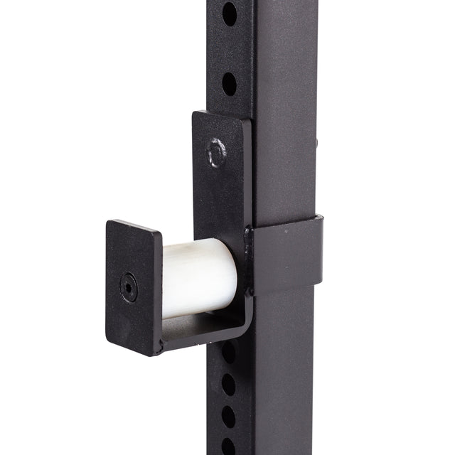 Close-up of the Bells of Steel Light Commercial Power Rack (2.3" x 2.3", ⅝" holes) in black metal, showing a J-cup barbell holder with height adjustment holes and a white protective insert for added barbell safety during workouts.