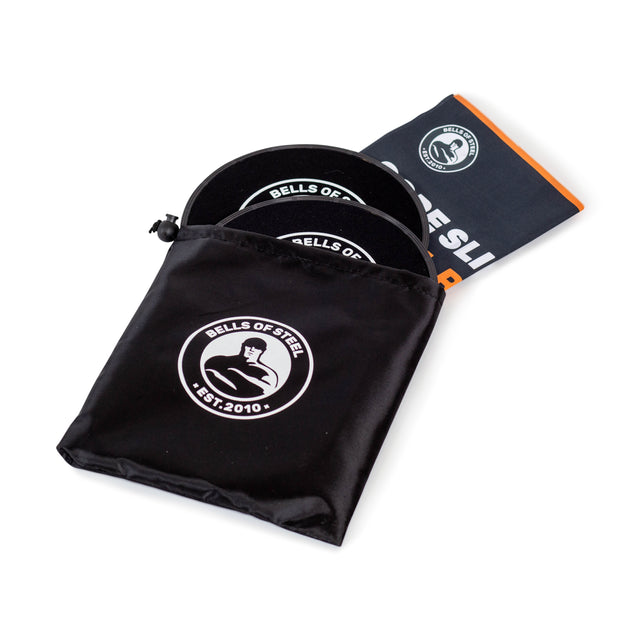 A Bells of Steel branded black pouch holds a pair of black Core Sliders and a folded workout poster with an orange edge, all shown on a white background—ideal for total body workouts.