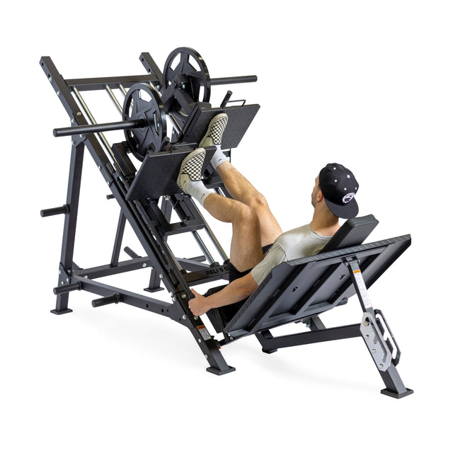 A man in athletic wear uses the Bells of Steel 2-in-1 Iso Leg Press & Hack Squat Machine (The Juggernaut), seated and pushing the footplate with both legs for a commercial gym leg workout.