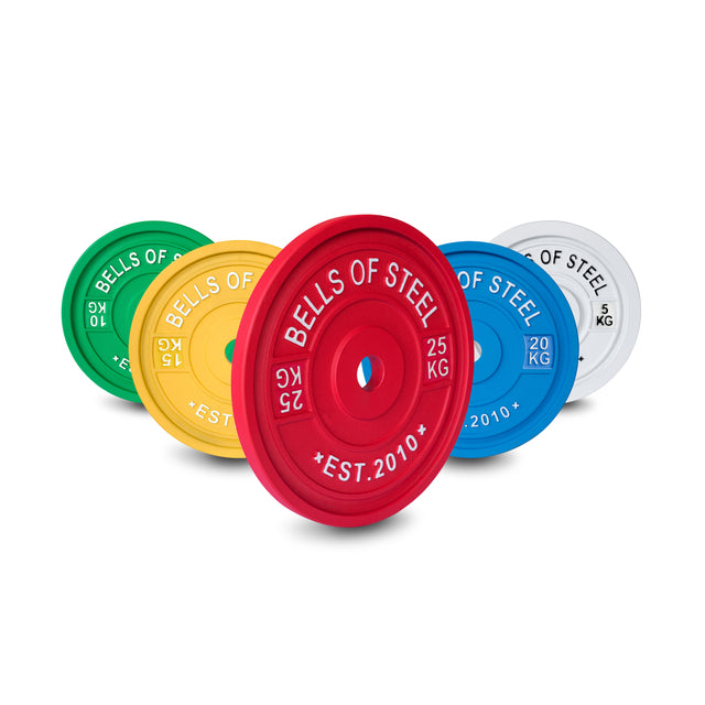 The Bells of Steel Calibrated Powerlifting Plates meet IPF specs and come in vibrant colors: white (5 kg), green (10 kg), yellow (15 kg), blue (20 kg), and red (25 kg). Each is color-coded and clearly marked in kilograms.