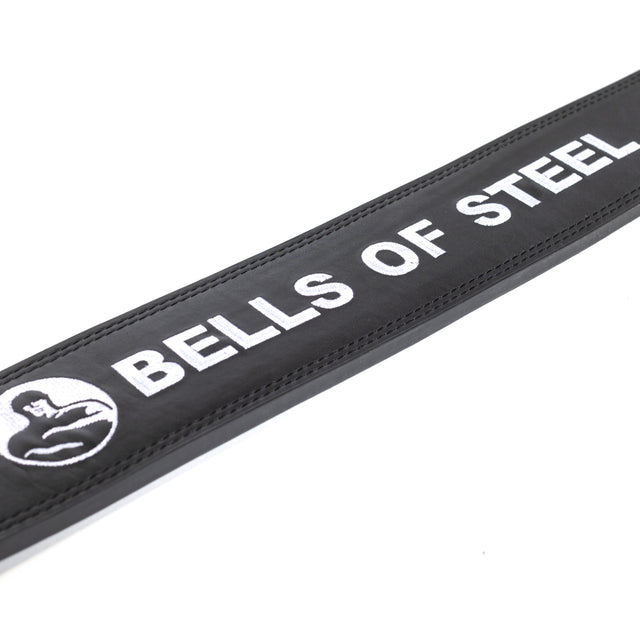 A close-up of the Bells of Steel Lever Belt in black with white stitching, featuring the brand name and muscular arm logo embroidered in whiteâideal for powerlifting enthusiasts.