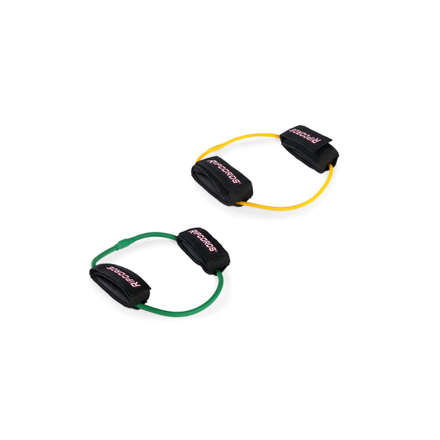 Two Human Trainer - Leg Cords by Bells of Steel—one yellow and one green—each feature black foam handles labeled “SPORTS” in pink and are displayed on a white background. These progressive tension leg bands are ideal for strengthening and toning your lower body.