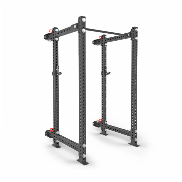The Bells of Steel Manticore Folding Power Rack – Prebuilt (3" x 3", 1" Holes) features black metal uprights, red safety catches, a pull-up bar, and adjustable attachments—ideal for home gym weightlifting and strength training.