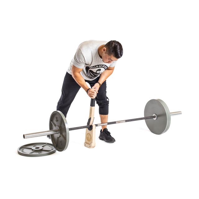 Using the Bells of Steel Meat Hook Deadlift Jack, a person in a gray t-shirt and black pants lifts one end of a loaded barbell to easily add or remove weight plates.