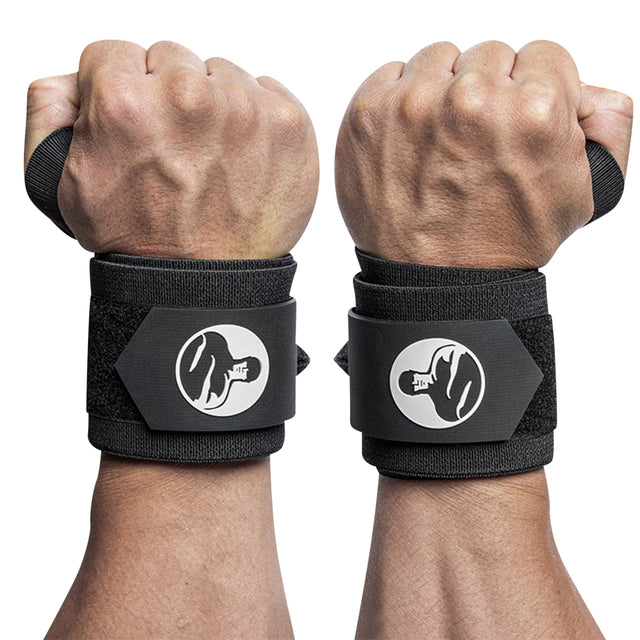 Two clenched fists sport Bells of Steel Mighty Wrist Wraps—black with white logos of a lifter and secured by Velcro—for essential wrist support and stability during heavy powerlifting.