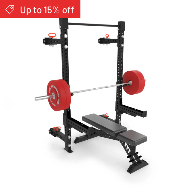A black and red Manticore Folding Half Rack Builder (3" x 3", 1" Holes) by Bells of Steel is shown with a loaded barbell, adjustable supports, and side attachments on a white background. "Up to 15% off" appears in the top left corner. Compatible with most home gym setups.