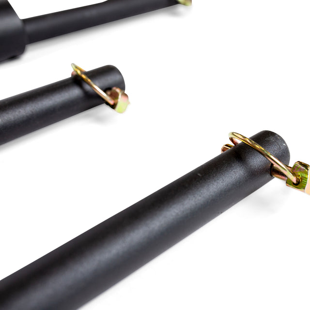 Close-up of three black metal Bells of Steel Pin Pipe Safeties with gold cotter pins on a white background—perfect for adding protection and stability to your power rack.