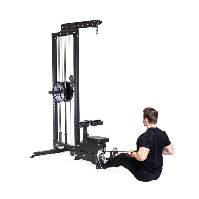 A person in a black t-shirt and pants uses the Bells of Steel Lat Pulldown Low Row Machine, featuring a sleek black design with an integrated weight stack and pulley system, as they pull the handle towards them while exercising.