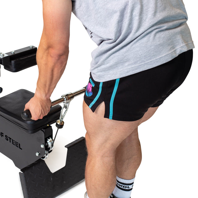 Wearing a gray shirt, black shorts, and white socks, a person grips the Bells of Steel Straight Bar Cable Attachment (20"), preparing for a strength exercise. Only the lower torso and legs are visible.