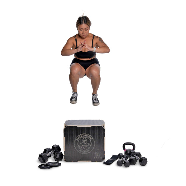 A woman in workout attire does a jump squat over a plyometric box with Bells of Steel Strength Circuit Starter Kits, including dumbbells, resistance bands, and a kettlebell, all set against a white background.