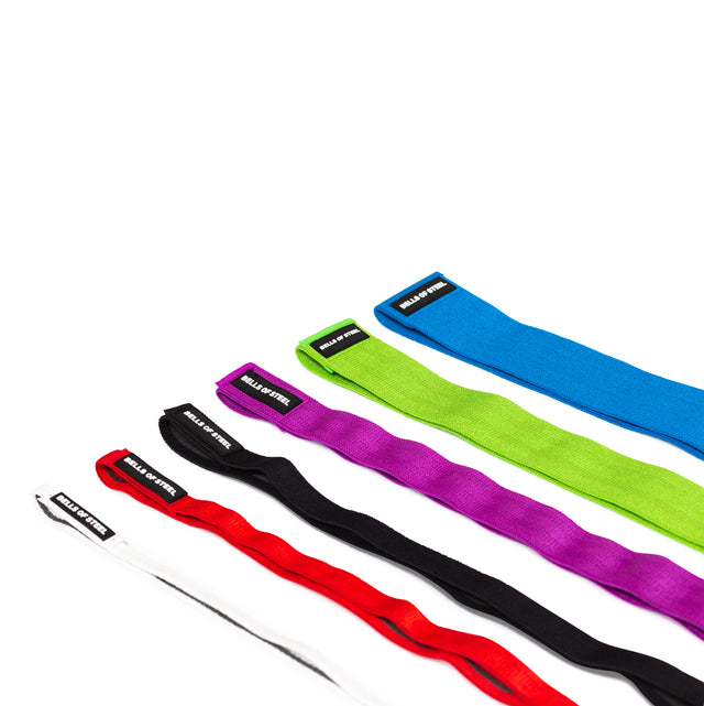 Five Bells of Steel 41" Fabric Non-Slip Resistance Bands in white, red, black, green, and blue are laid out diagonally on a white surface. Each band has a small black label with white text—ideal for powerlifting or mobility work.