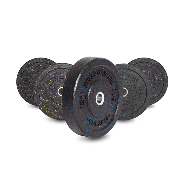 The Bells of Steel Crumb Bumper Plates set includes six durable plates in vibrant speckled black, blue, yellow, and green. Each plate has a stainless steel insert ring for easy barbell attachment and is displayed upright to highlight its design.