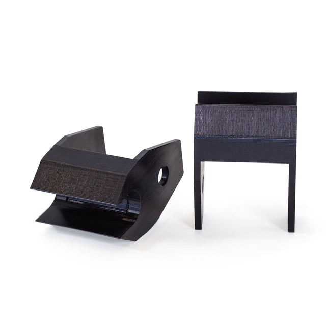 Two black, geometric Above Rack Barbell Holder parts by Bells of Steel stand upright on a white background—one is angled with a hole like a barbell holder, the other stands vertically with two legs.