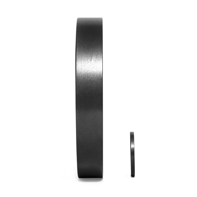 A large Black Mighty Grip Olympic Weight Plate by Bells of Steel stands upright on a white background next to a smaller one, highlighting their ergonomic design and variation in size for optimal precision grip.