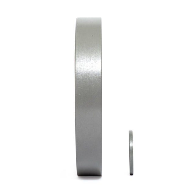 A side view of two metallic cylindrical discs on a white background displays the larger "Gray Mighty Grip Olympic Weight Plate" by Bells of Steel. This plate is significantly wider and taller than the smaller one, highlighting a clear size difference.